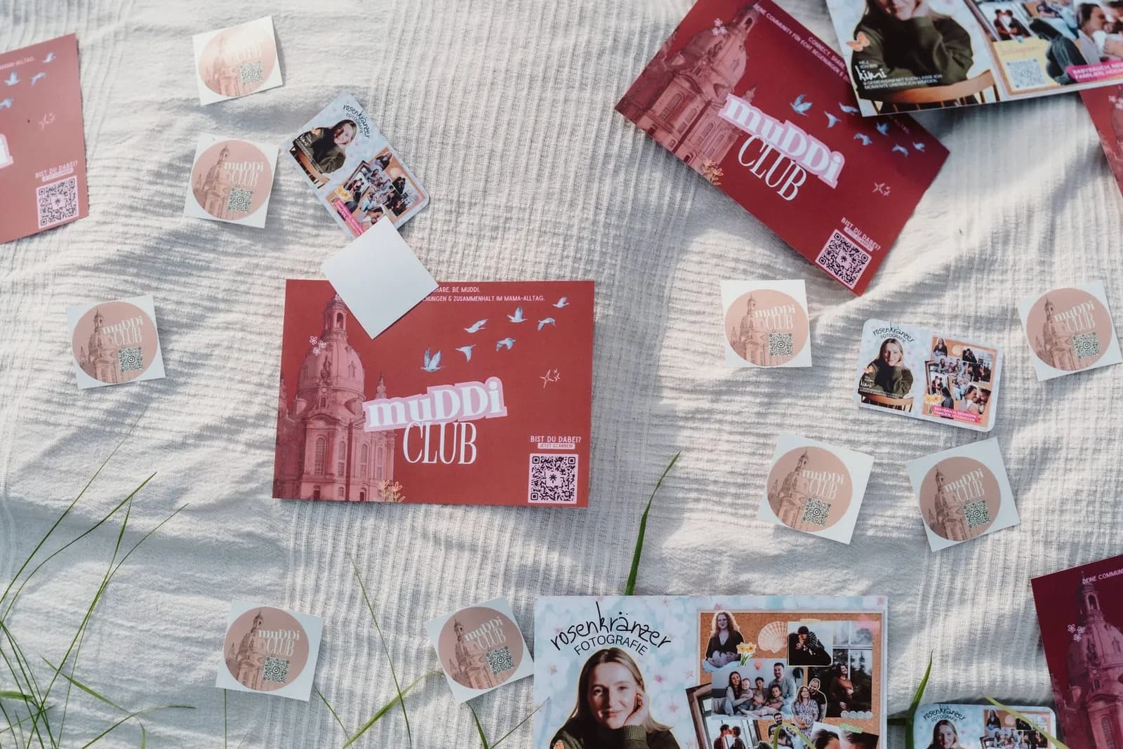 Flyer und Sticker vom muDDi Club liegen auf einer Picknickdecke